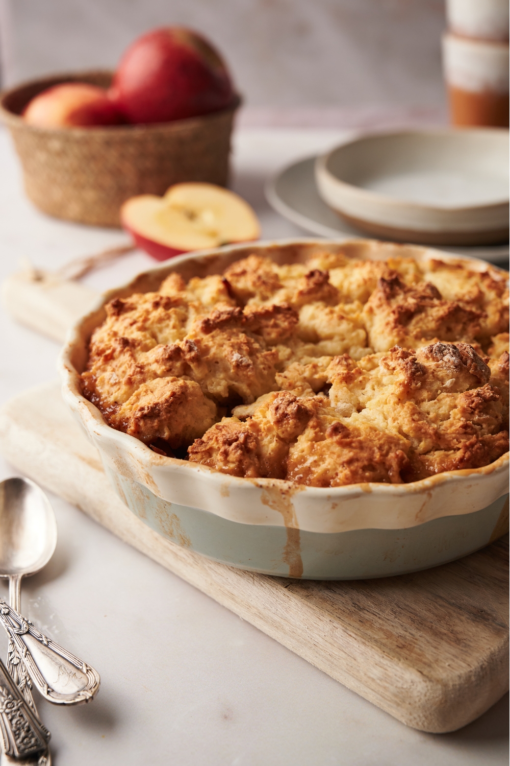 Apple cobbler in a pie dish on a wooden serving board.