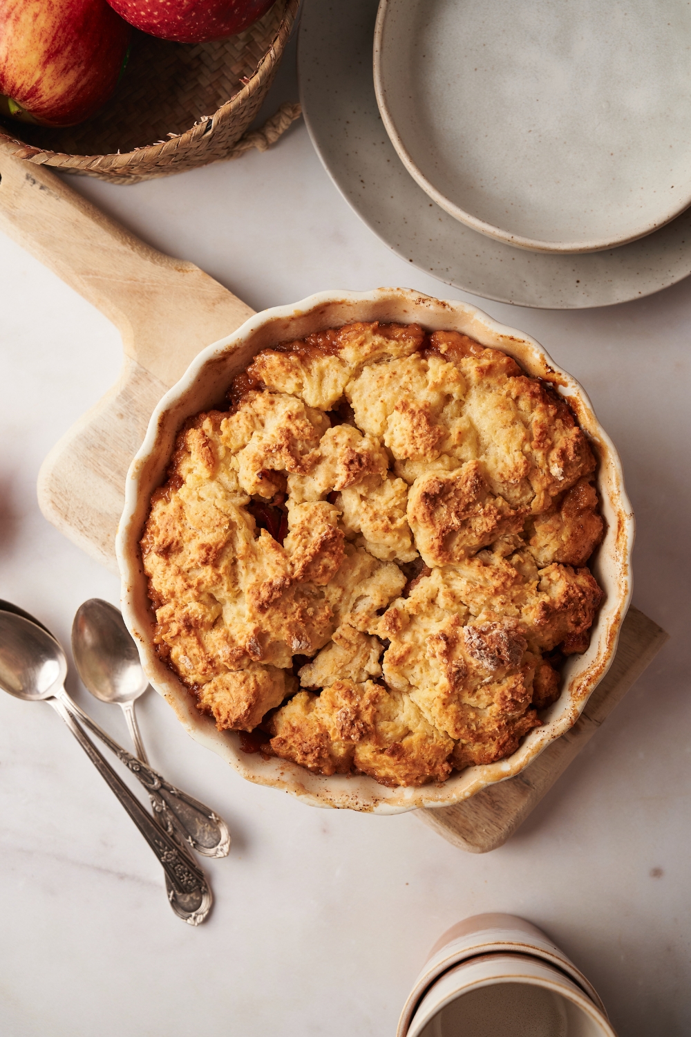 Apple cobbler in a pie dish on a wooden serving board.