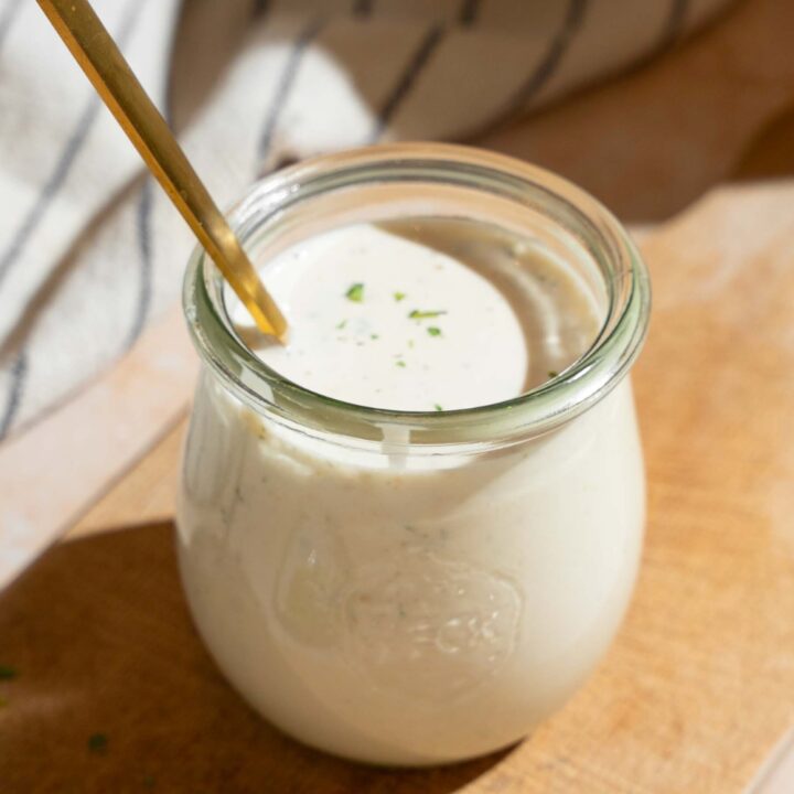 A jar of wingstop ranch dressing with a spoon submerged in it.