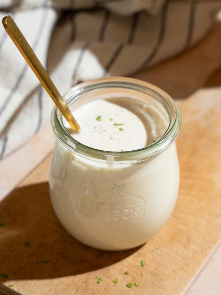 A jar of wingstop ranch dressing with a spoon submerged in it.
