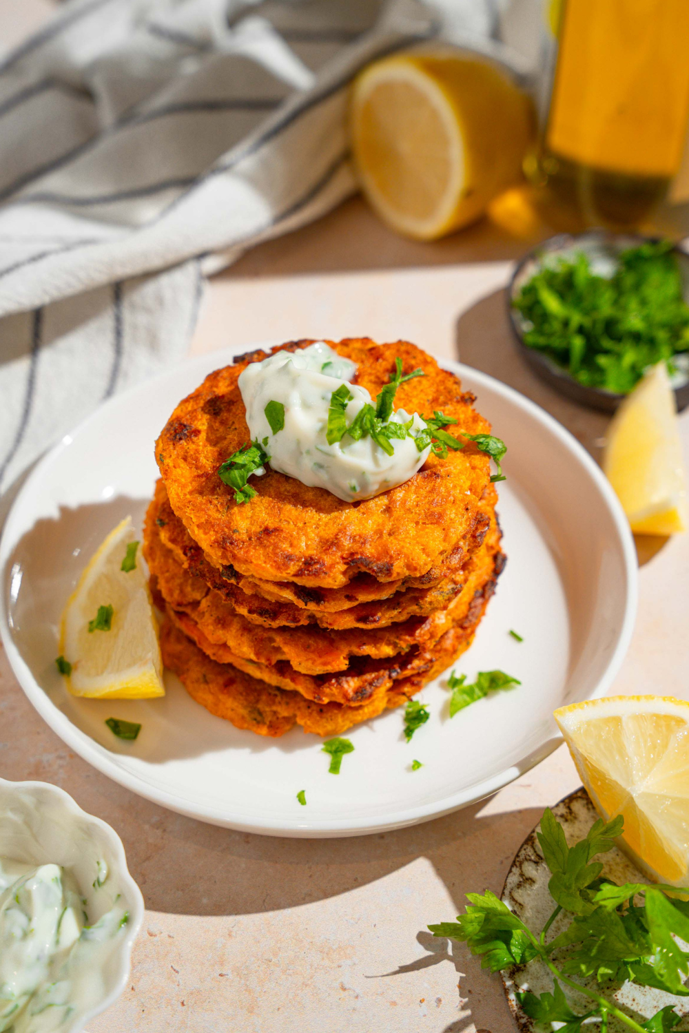 Six sweet potato patties, stacked on top of one another on a white plate.