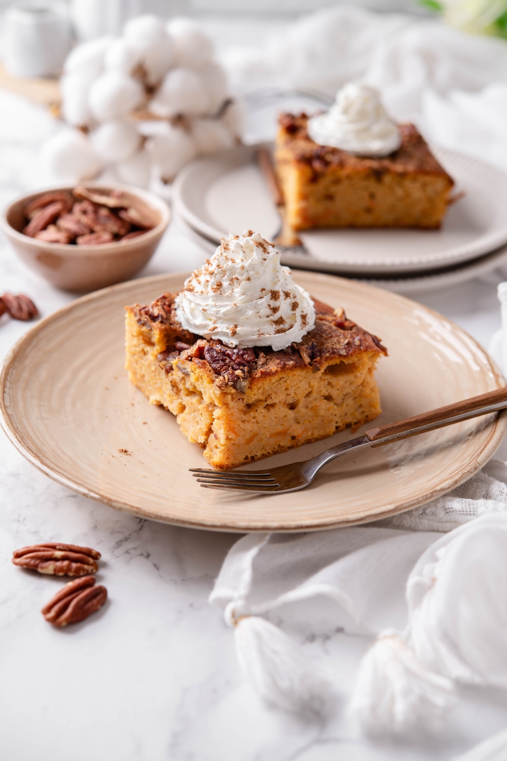 A plate with pumpkin dump cake topped with whipped cream and sprinkled with cinnamon.