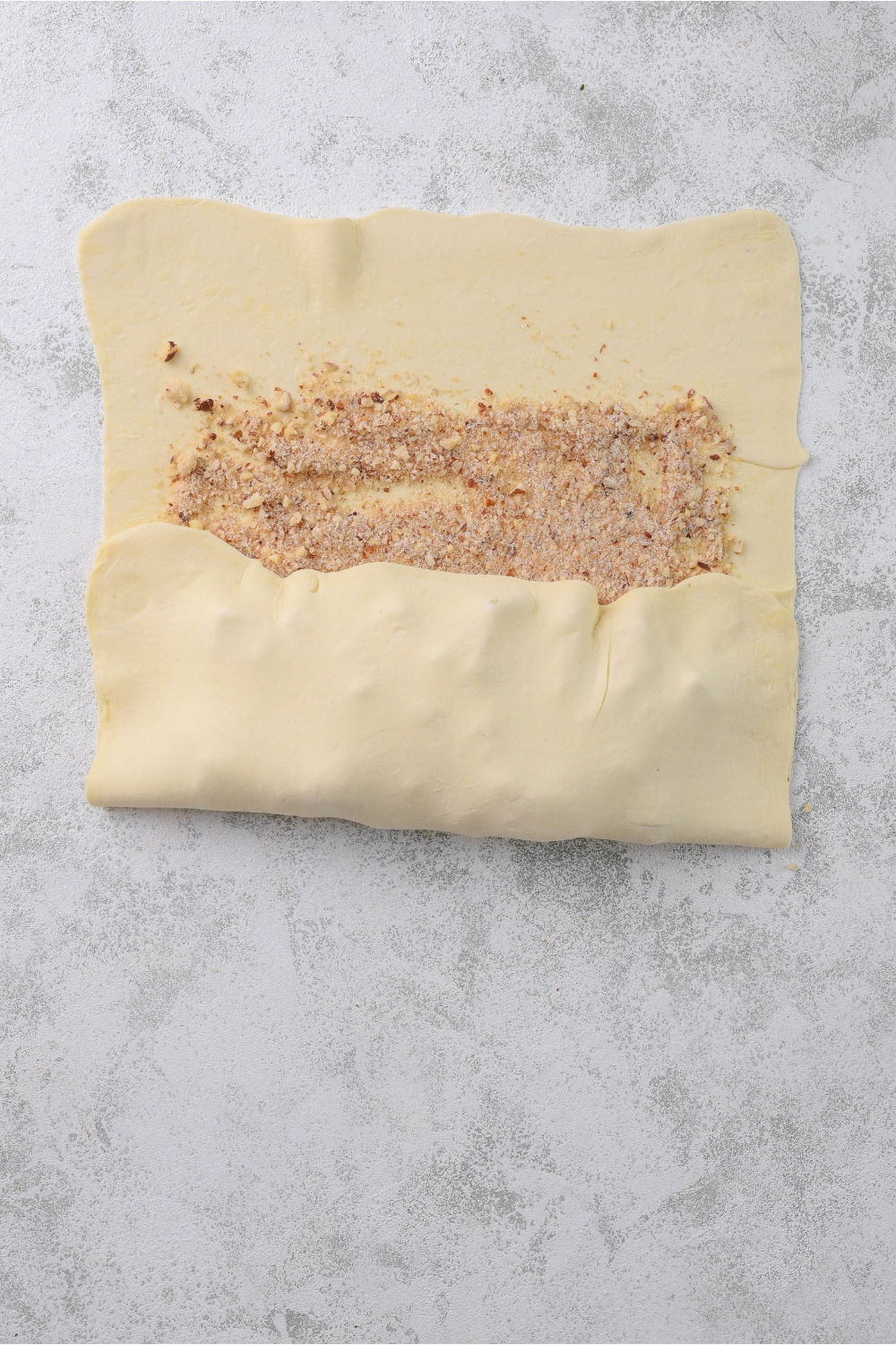 Apple strudel filling being folded into a puff pastry sheet.