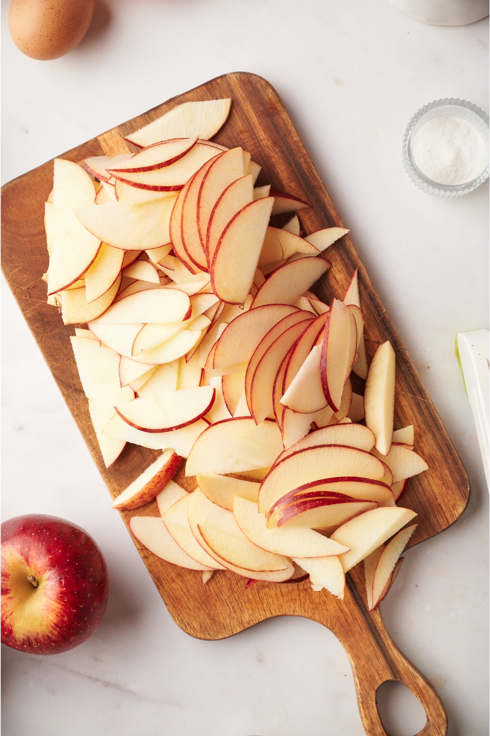 A wooden cutting board with sliced apples.