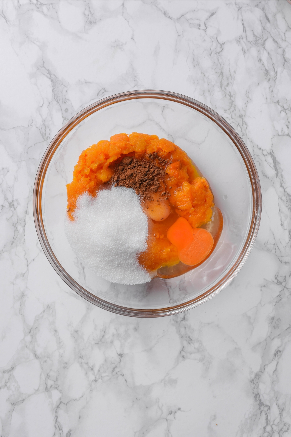 A mixing bowl with pumpkin puree, sugar, spices, and an egg.