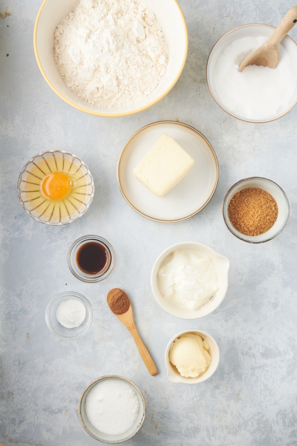 flour, an egg, vanilla, butter, buttermilk, all in separate bowls on a white counter