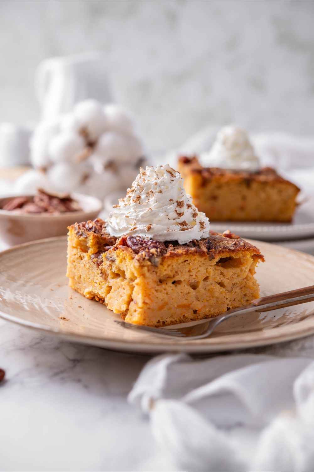 A plate with pumpkin dump cake topped with whipped cream and sprinkled with cinnamon.