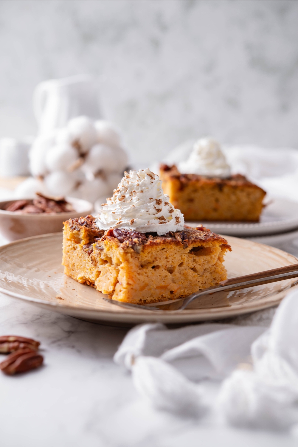 A plate with pumpkin dump cake topped with whipped cream and sprinkled with cinnamon.