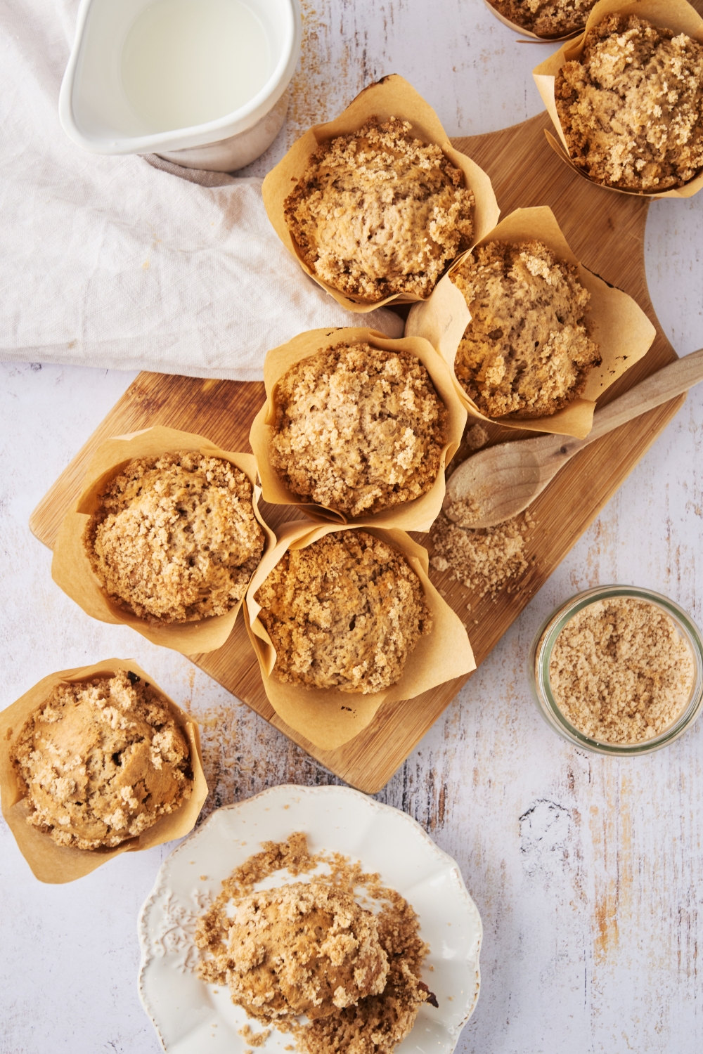 An overhead view of cinnamon streusel muffins on a serving board with some on a serving plate.