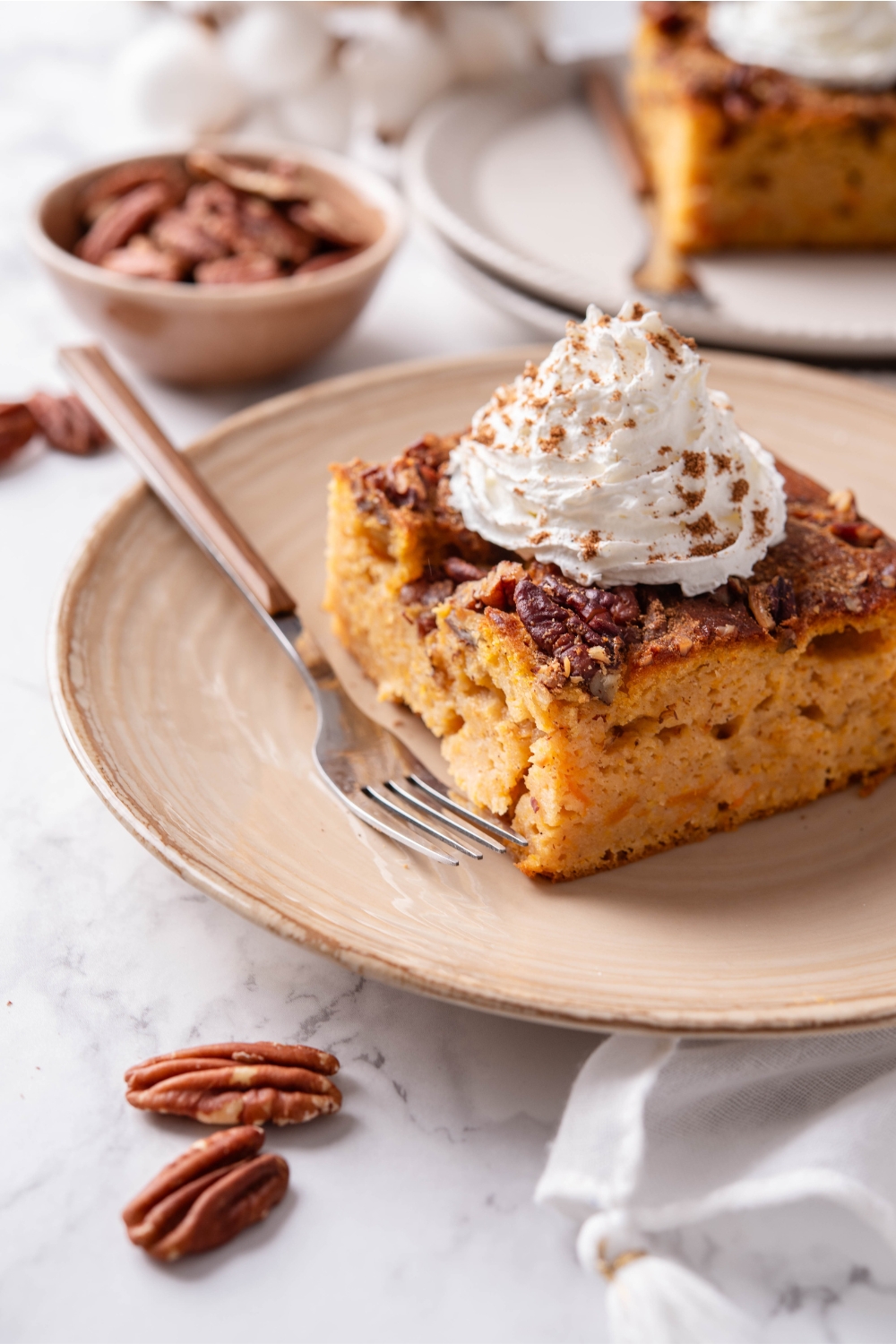 A plate with pumpkin dump cake topped with whipped cream and sprinkled with cinnamon.