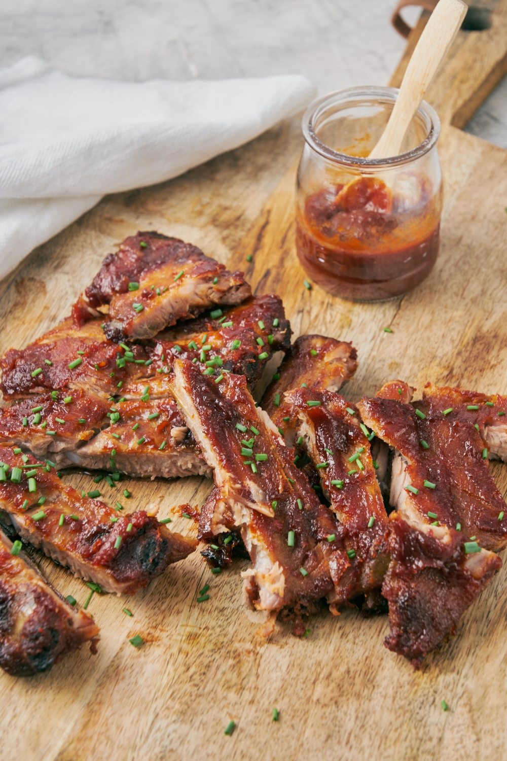 A bunch of riblets on a wooden cutting board.