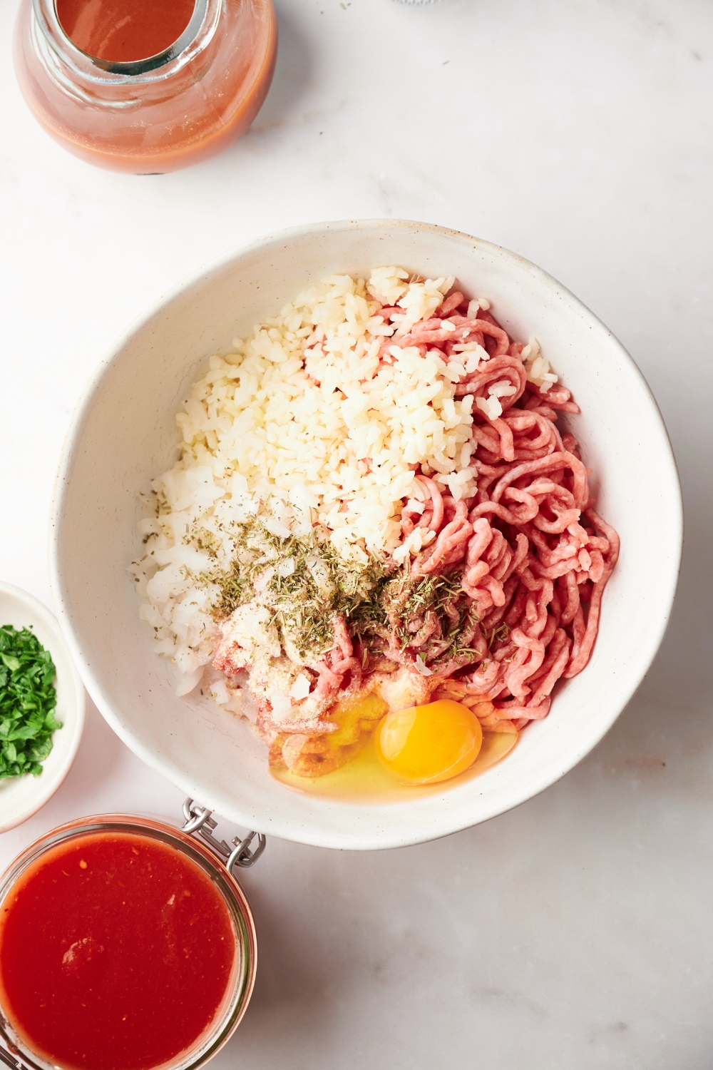 rice, ground beef, an egg, and ground pepper in a white mixing bowl