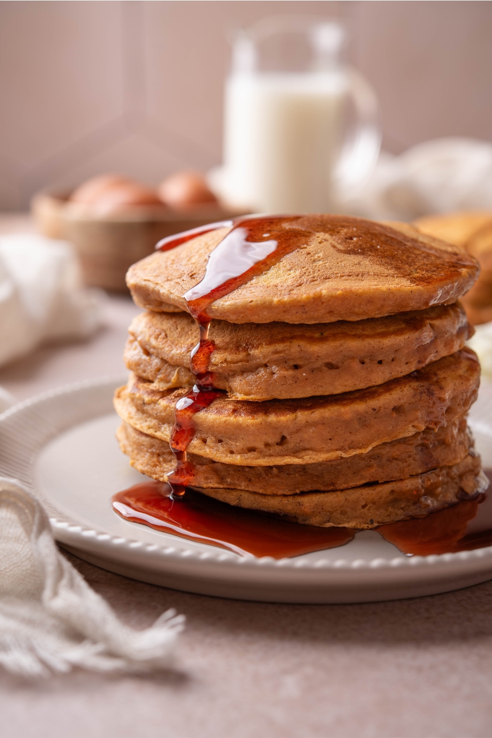 A plate with a stack of sweet potato pancakes with syrup drizzled over them.