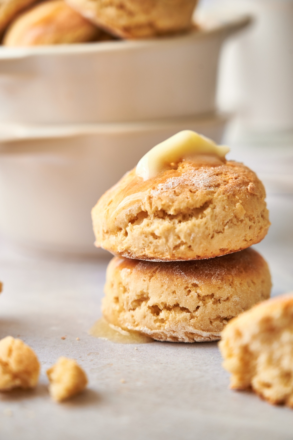Two biscuits are stacked on top of each other. The top biscuit has a dollop of butter on top.