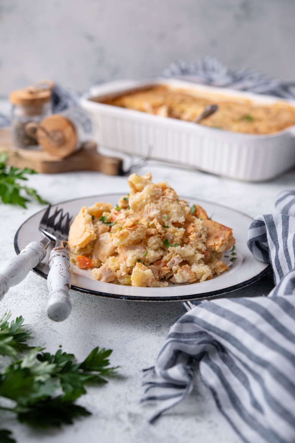 A plate filled with chicken pot pie and crescent roll crust. The pot pie is garnished with herbs and there are two forks on the plate.