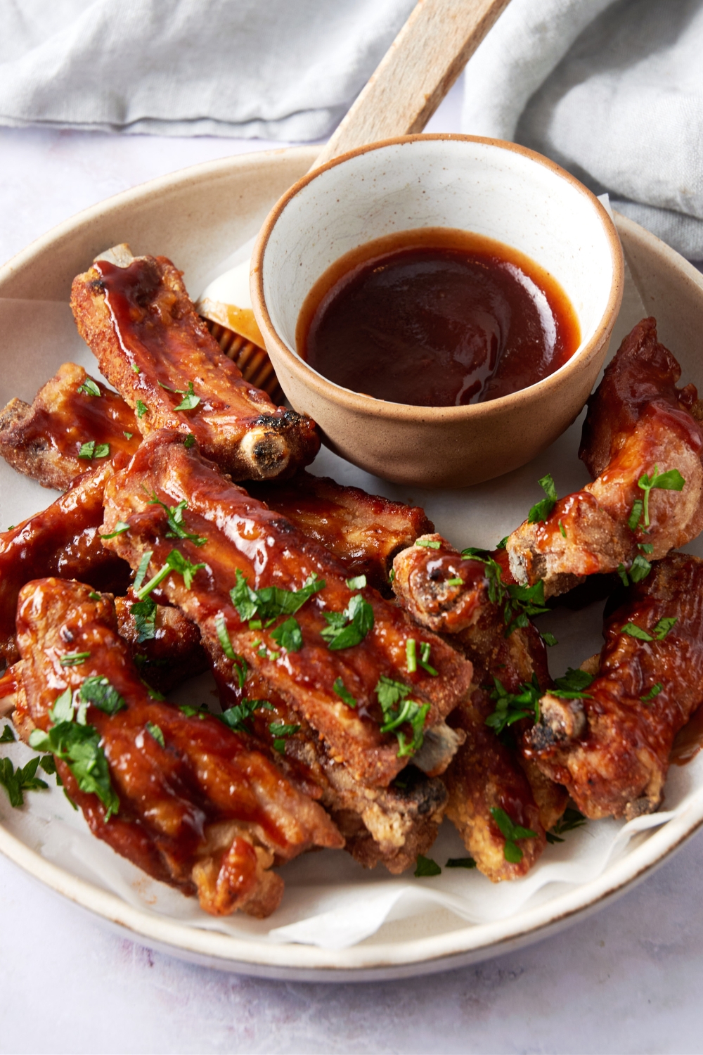 A plate of fried ribs covered in sauce and garnished with fresh herbs.