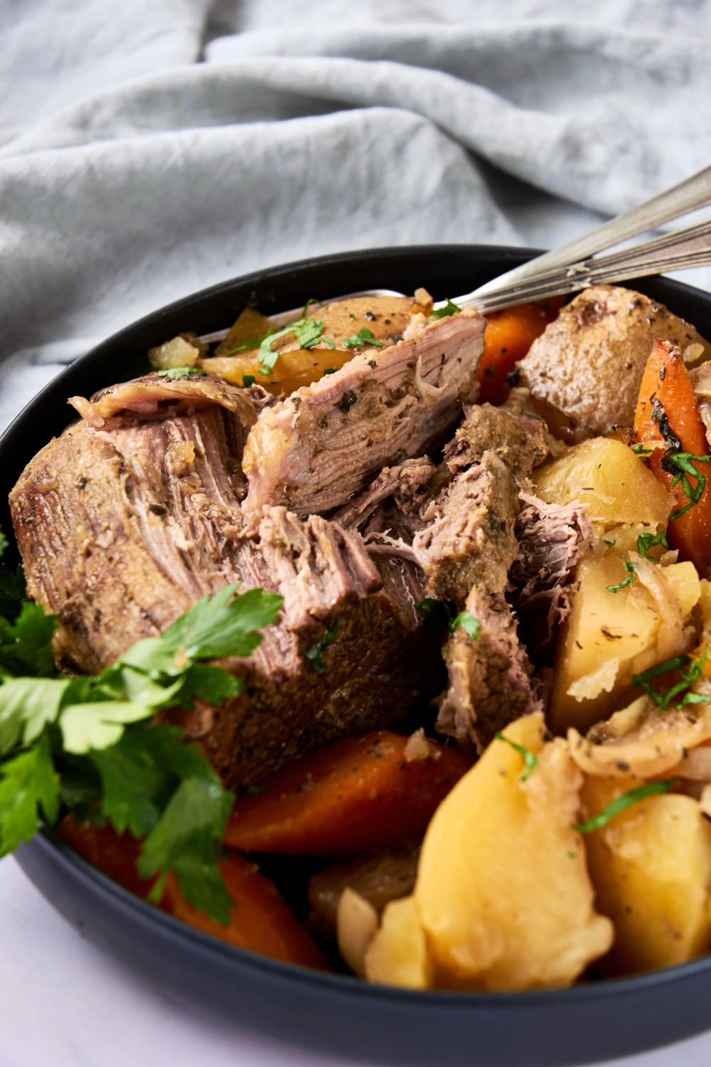 A full dish of roast and veggies. The dish has been garnished with fresh parsley.