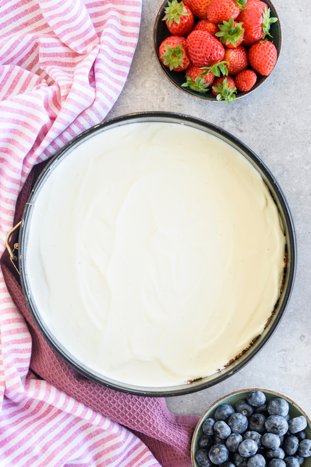 A Cool Whip pie next to bowls of blueberries and strawberries.