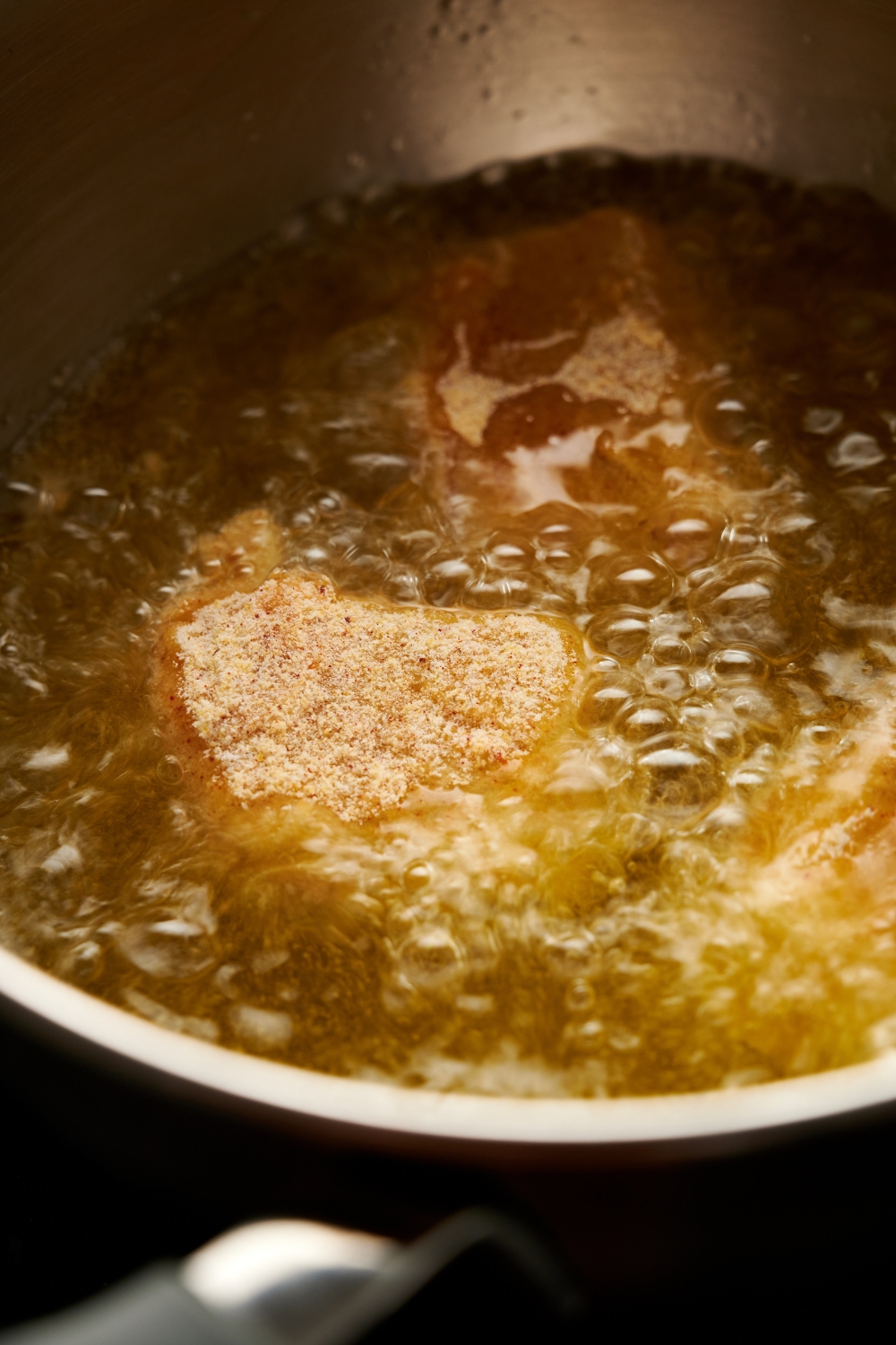 A pot of bubbling oil with catfish nuggets in it.