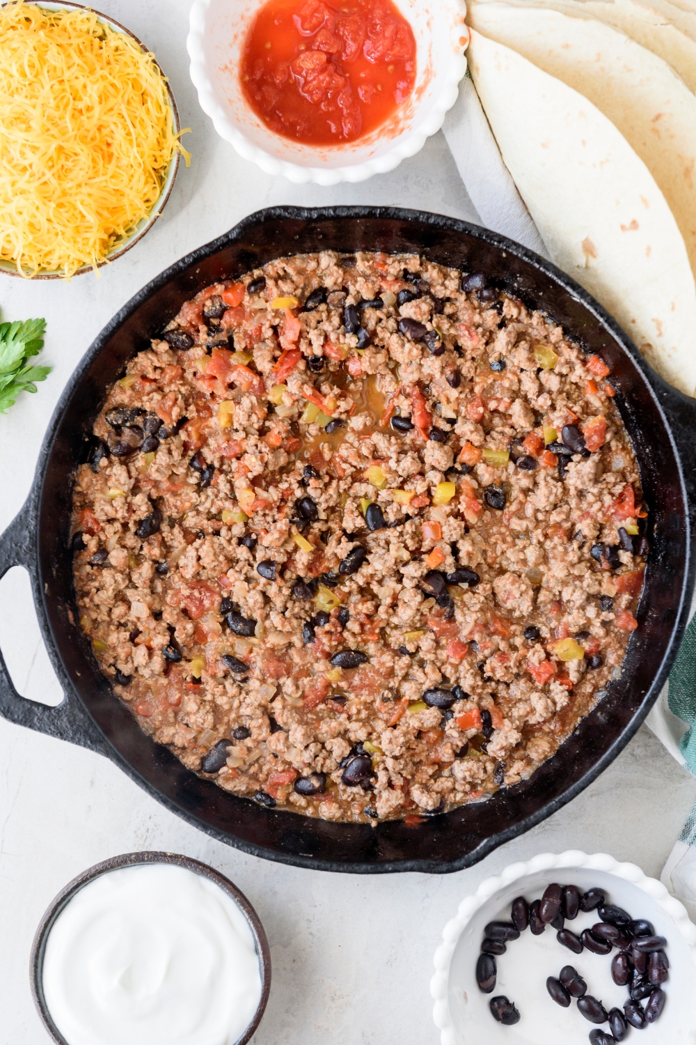 A skillet filled with ground beef, diced peppers, and black beans and tomatoes.