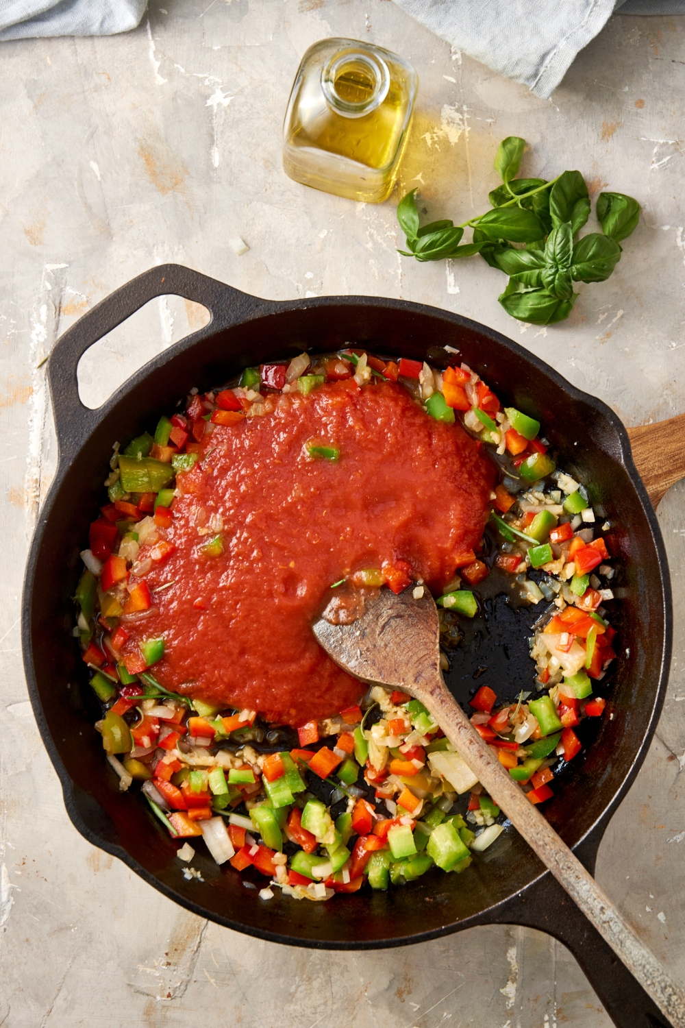 Tomato sauce is added to the cast iron pan full of peppers and onions.