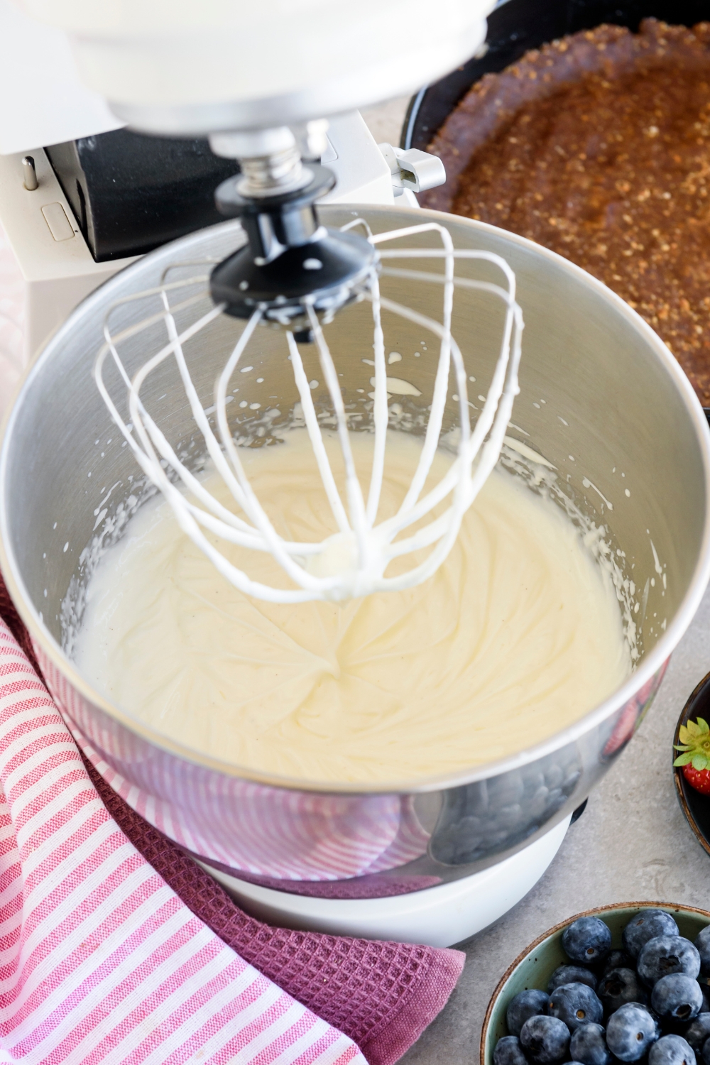 A standing mixer filled with a blended creamy mixture.