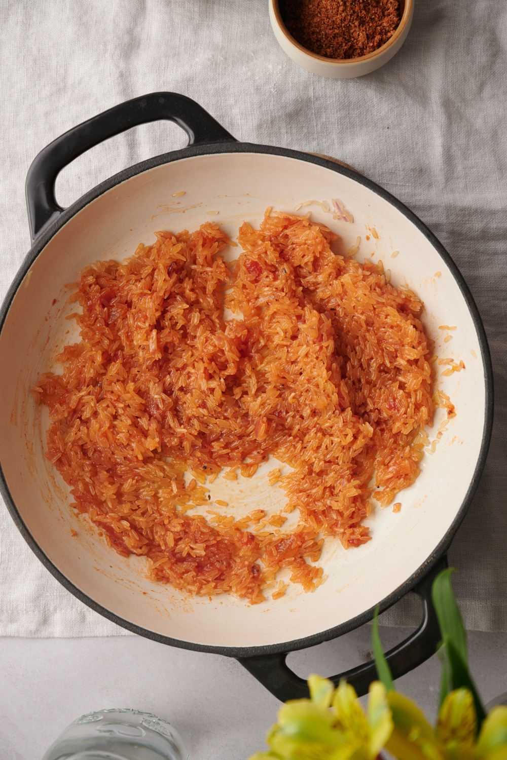 Tomato sauce and rice are combined with the cooked onion and garlic in a large white pot.