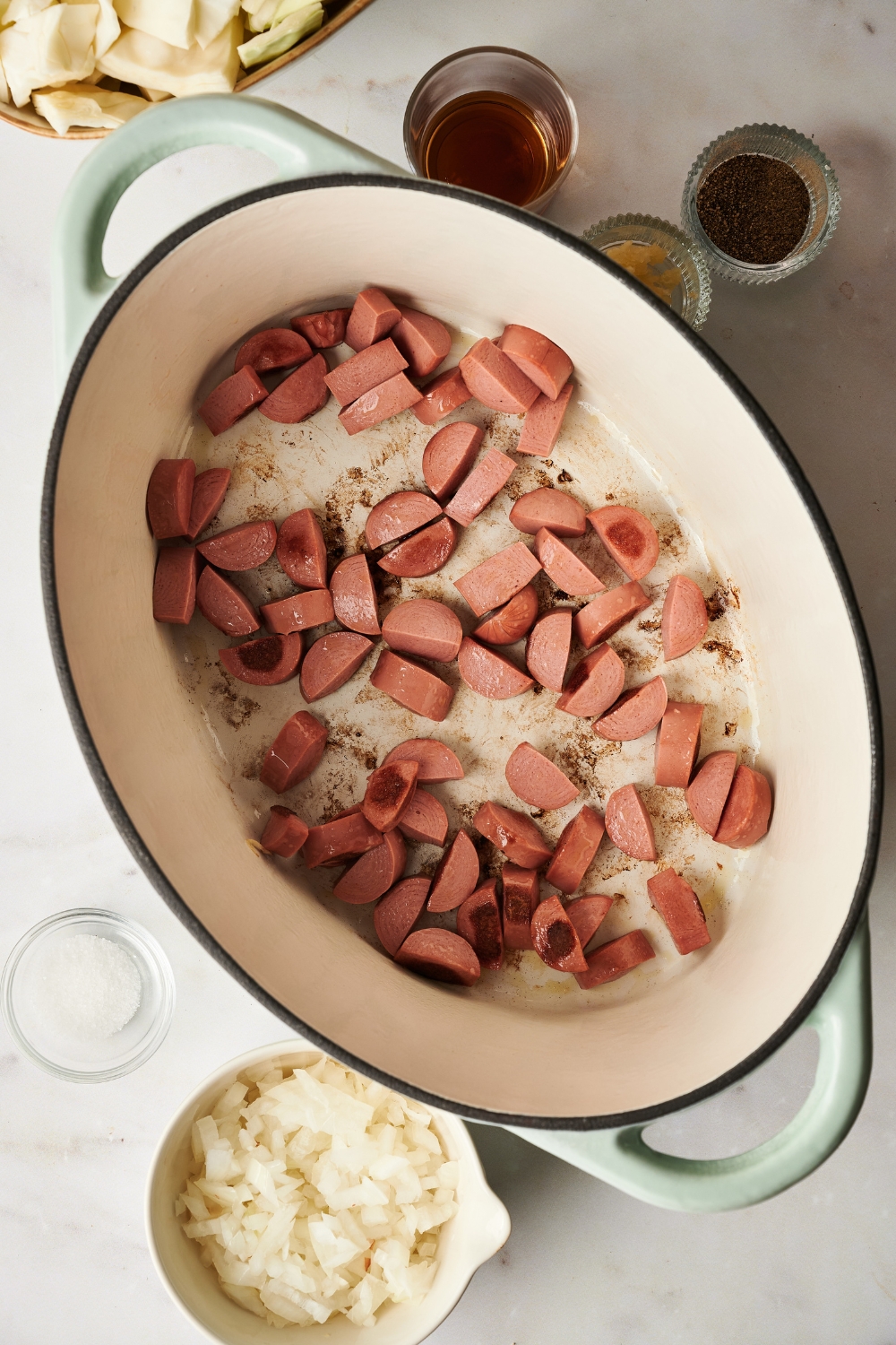 A Dutch oven filled with diced sausages cooking in it.