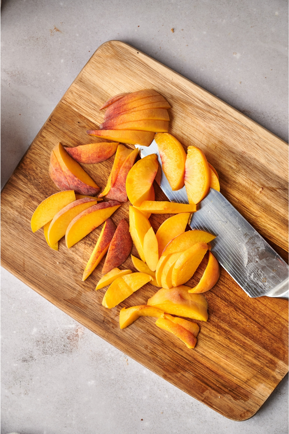 A wooden cutting board with sliced peaches.