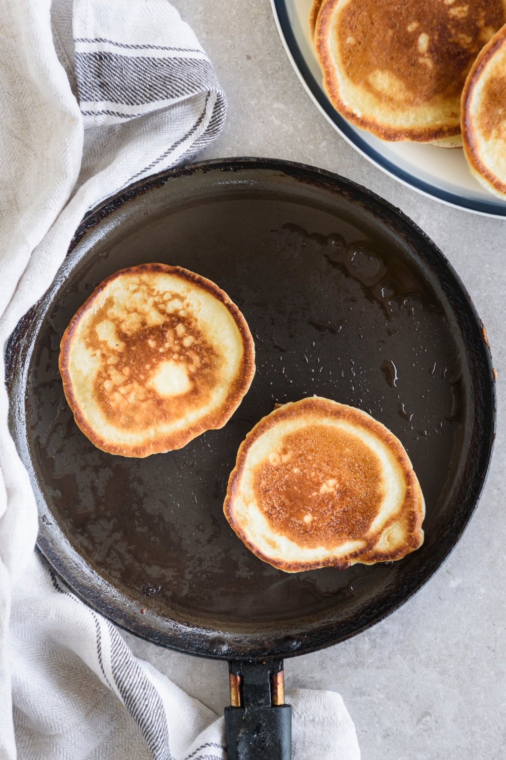 A griddle with two cooked pancakes on it.