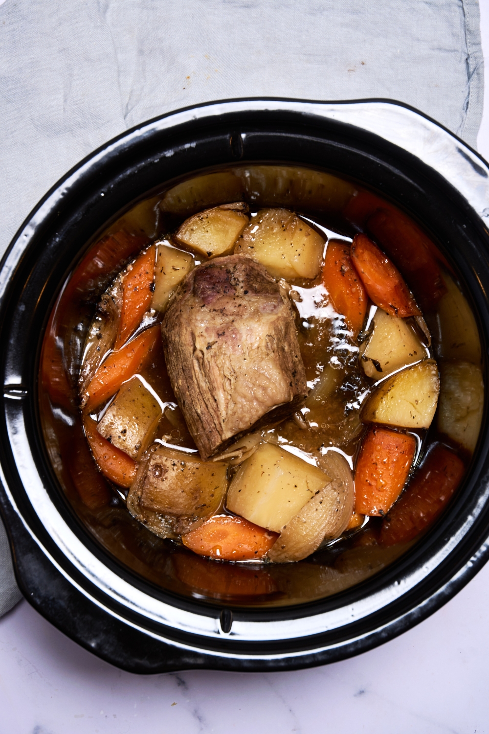A cooked roast and vegetables sit in the slow cooker.