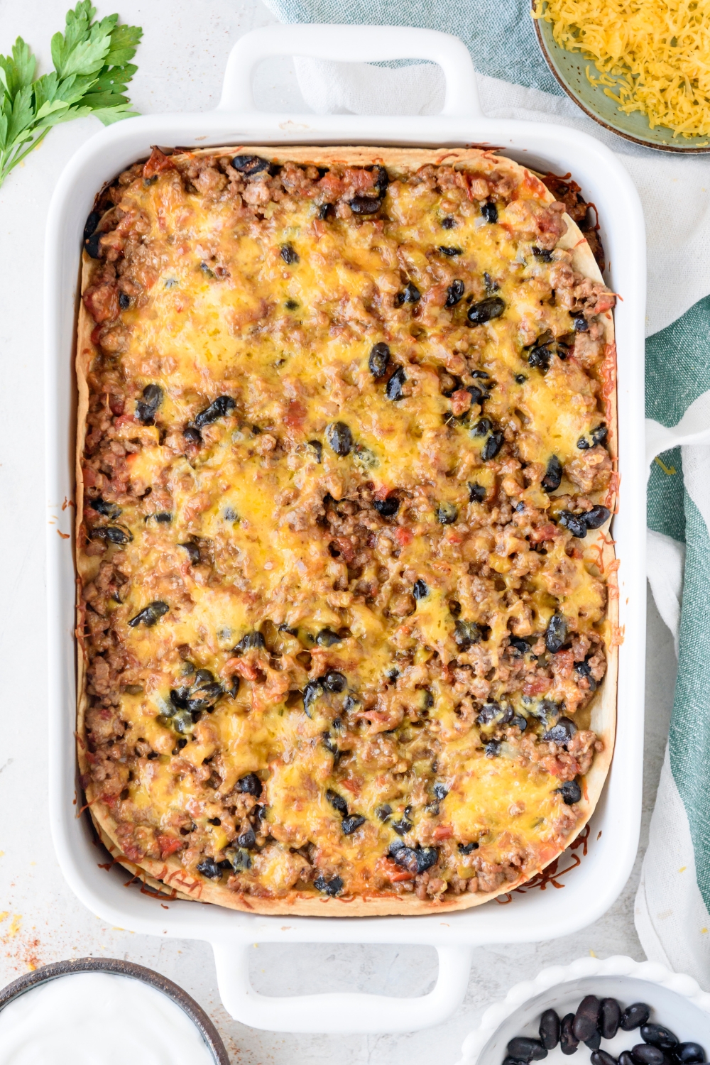 A baking dish filled with baked Mexican lasagna topped with melted cheese.