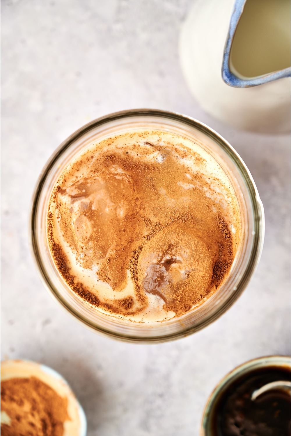 An overhead view of a glass with Iced Brown Sugar Oatmilk Shaken Espresso topped with cinnamon.