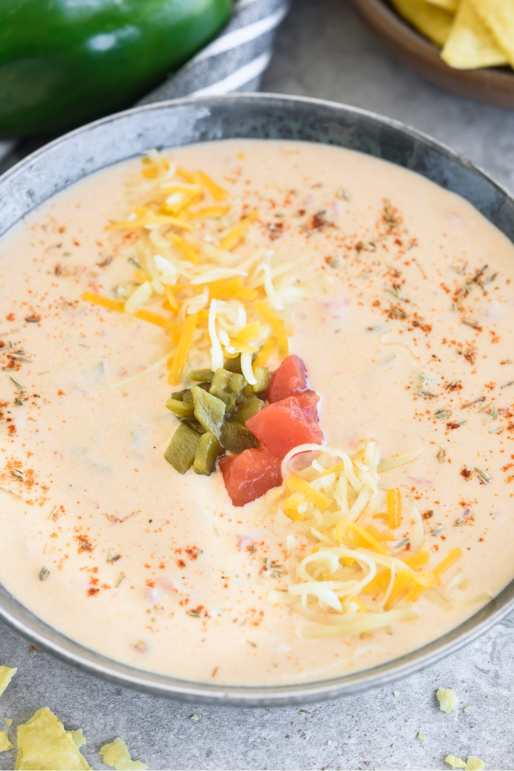 A bowl with the queso topped with extra cheese, peppers, and tomatoes.
