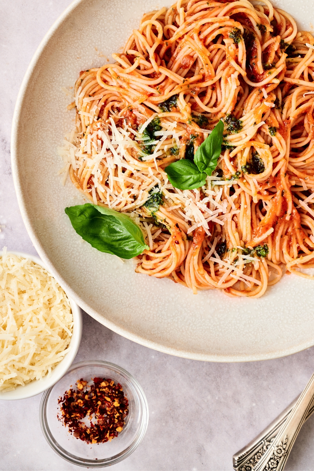 Spaghetti pomodoro in a white bowl garnished with basil and cheese.