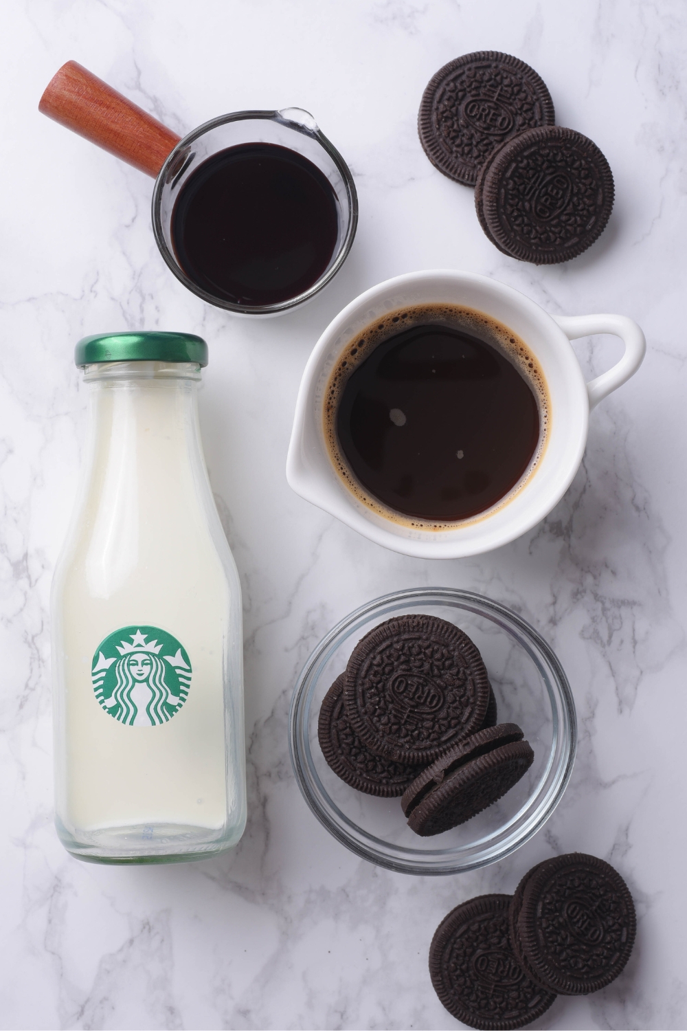 A countertop with a milk jug, Oreos, and coffee in separate containers.