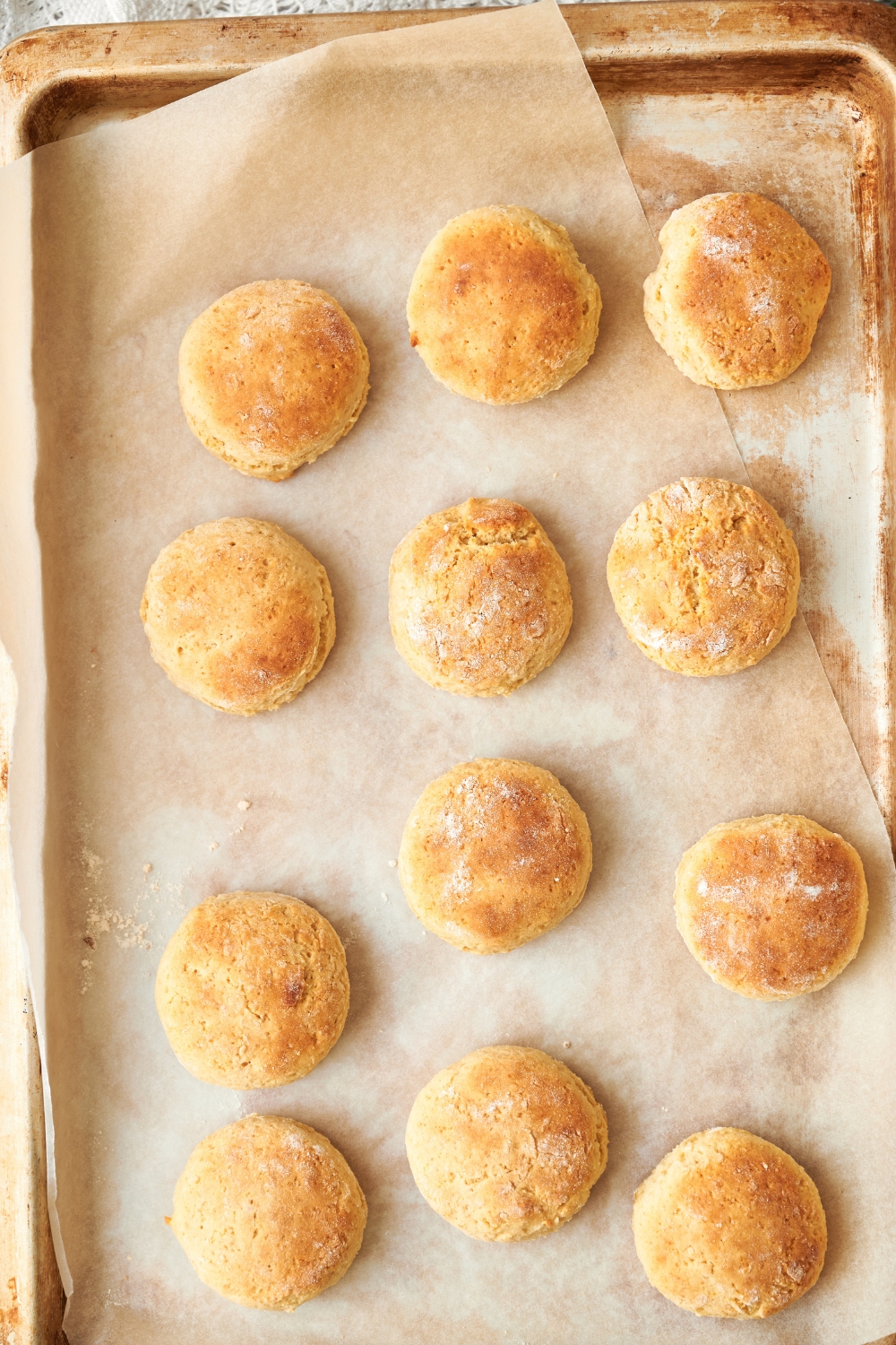 Twelve golden brown biscuits lined neatly on a parchment paper lined baking sheet.