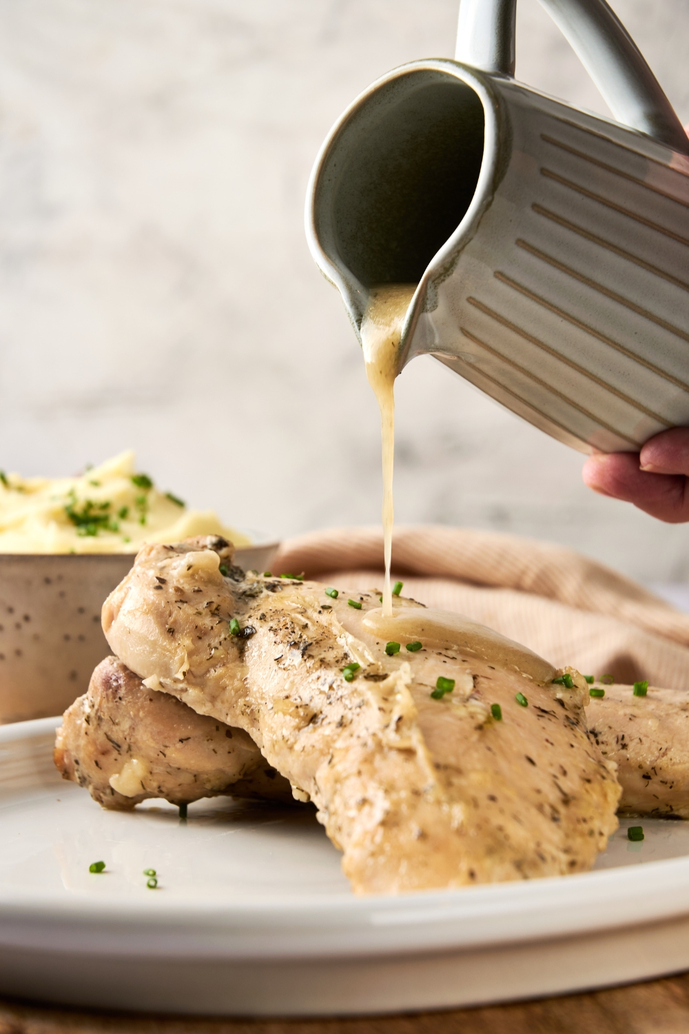 A serving tray with cooked turkey meat being topped with butter sauce.