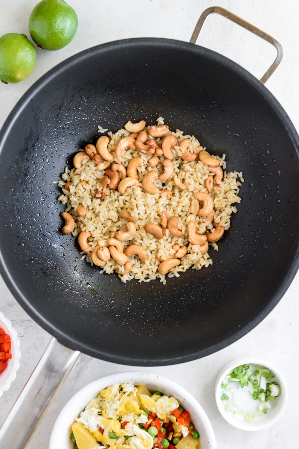 A wok with cooked rice and cashews.