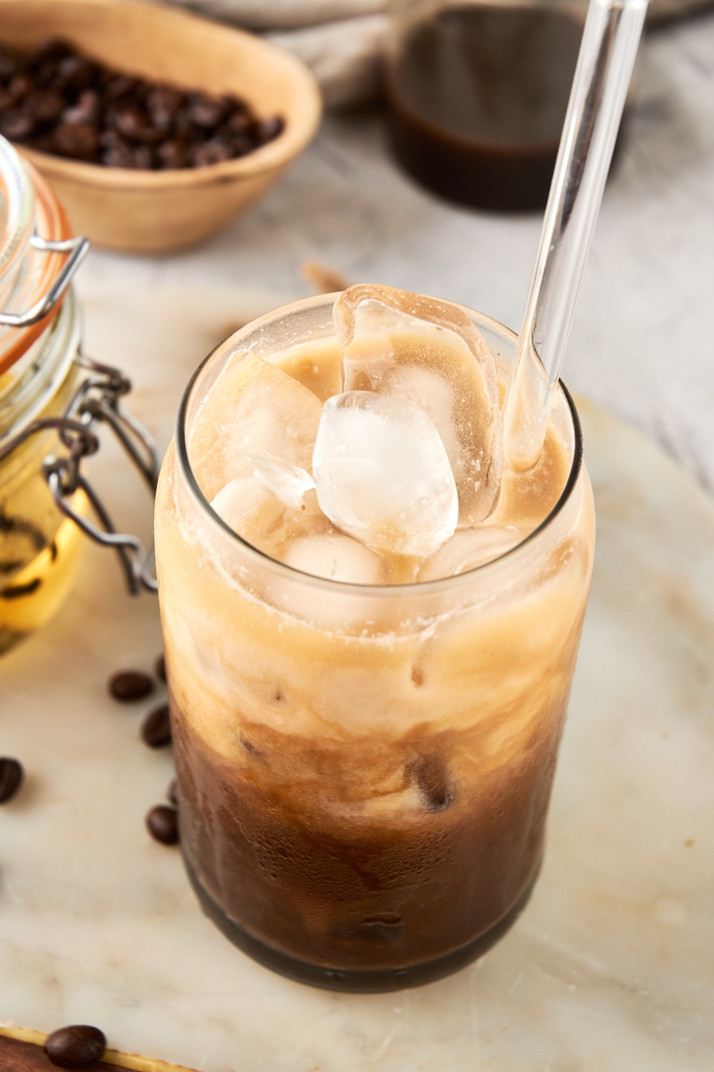 A glass with iced toasted vanilla shaken espresso with a glass straw in it.