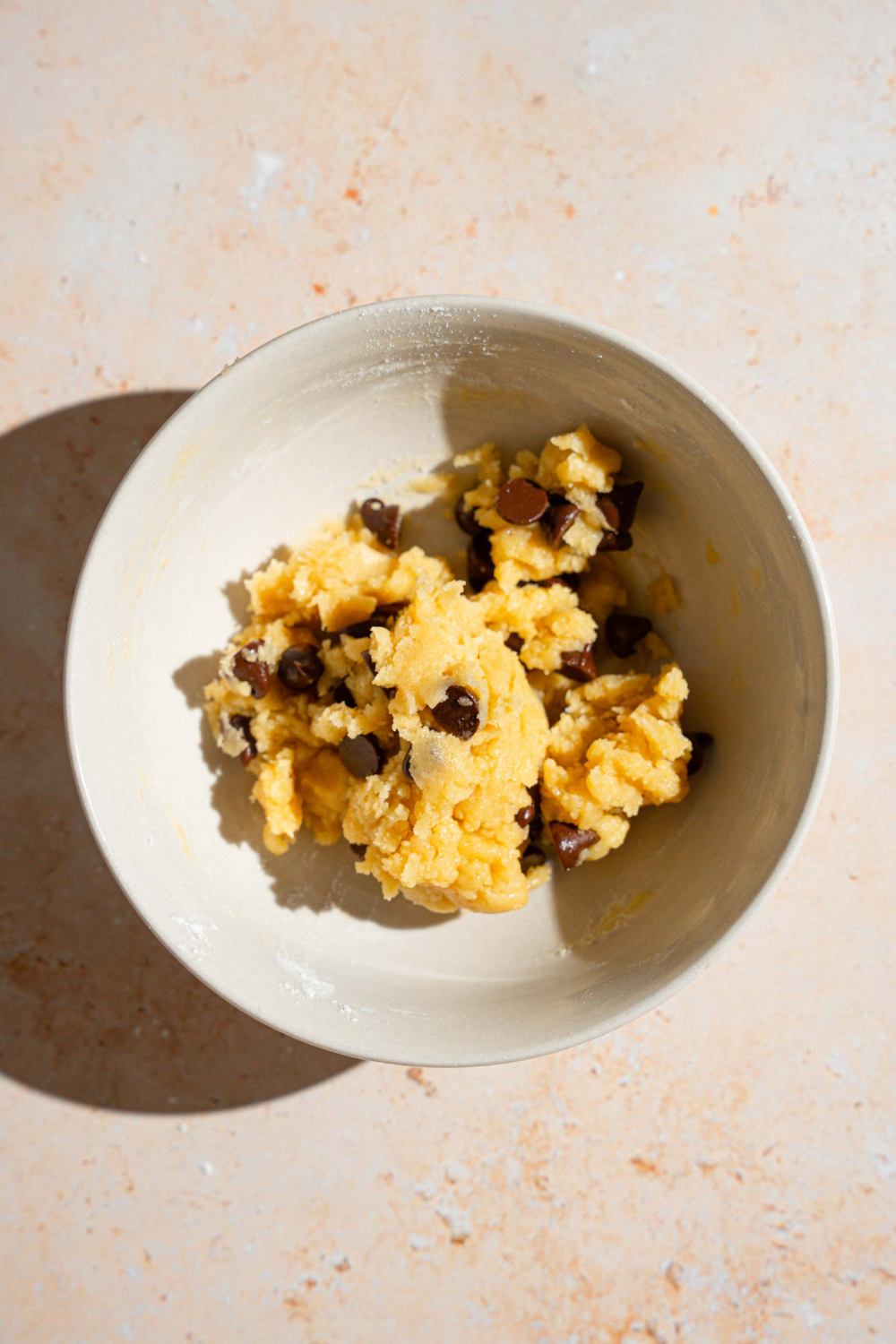 A bowl of chocolate chip cookie dough in a white bowl.