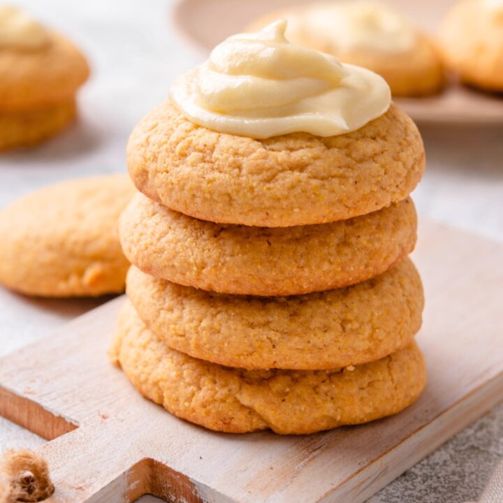 Four cornbread cookies stacked on top of one another. The top cookie is covered in a buttercream frosting.