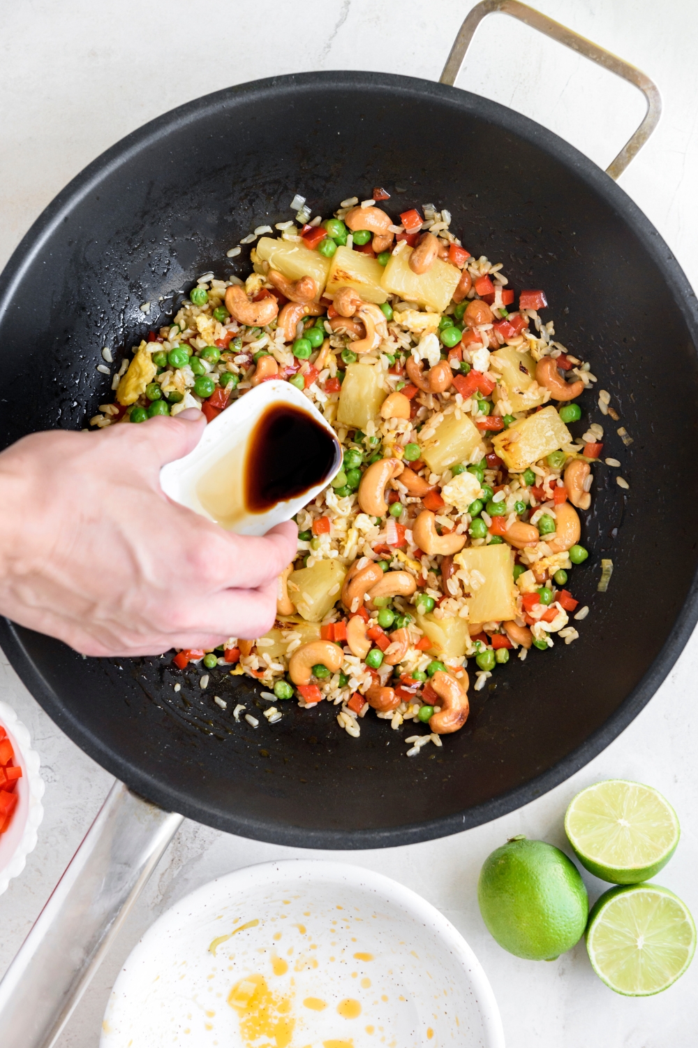 A wok with soy sauce being added to the ingredients.