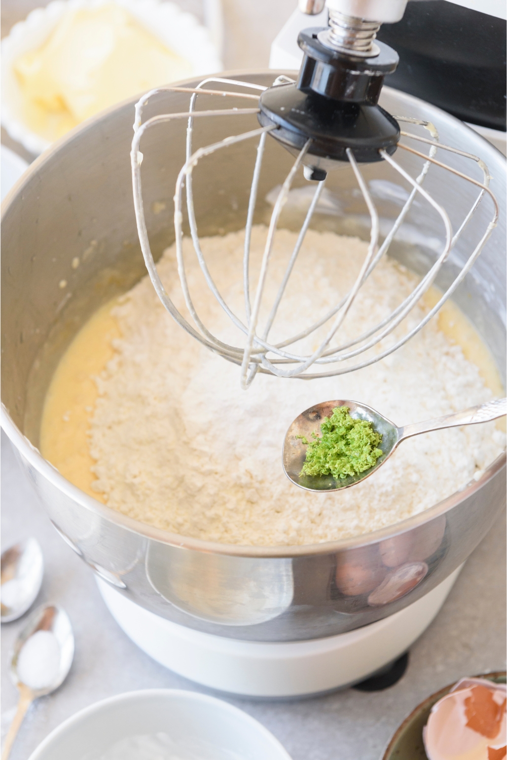 A stand mixer with dry ingredients being added to the wet ingredients.