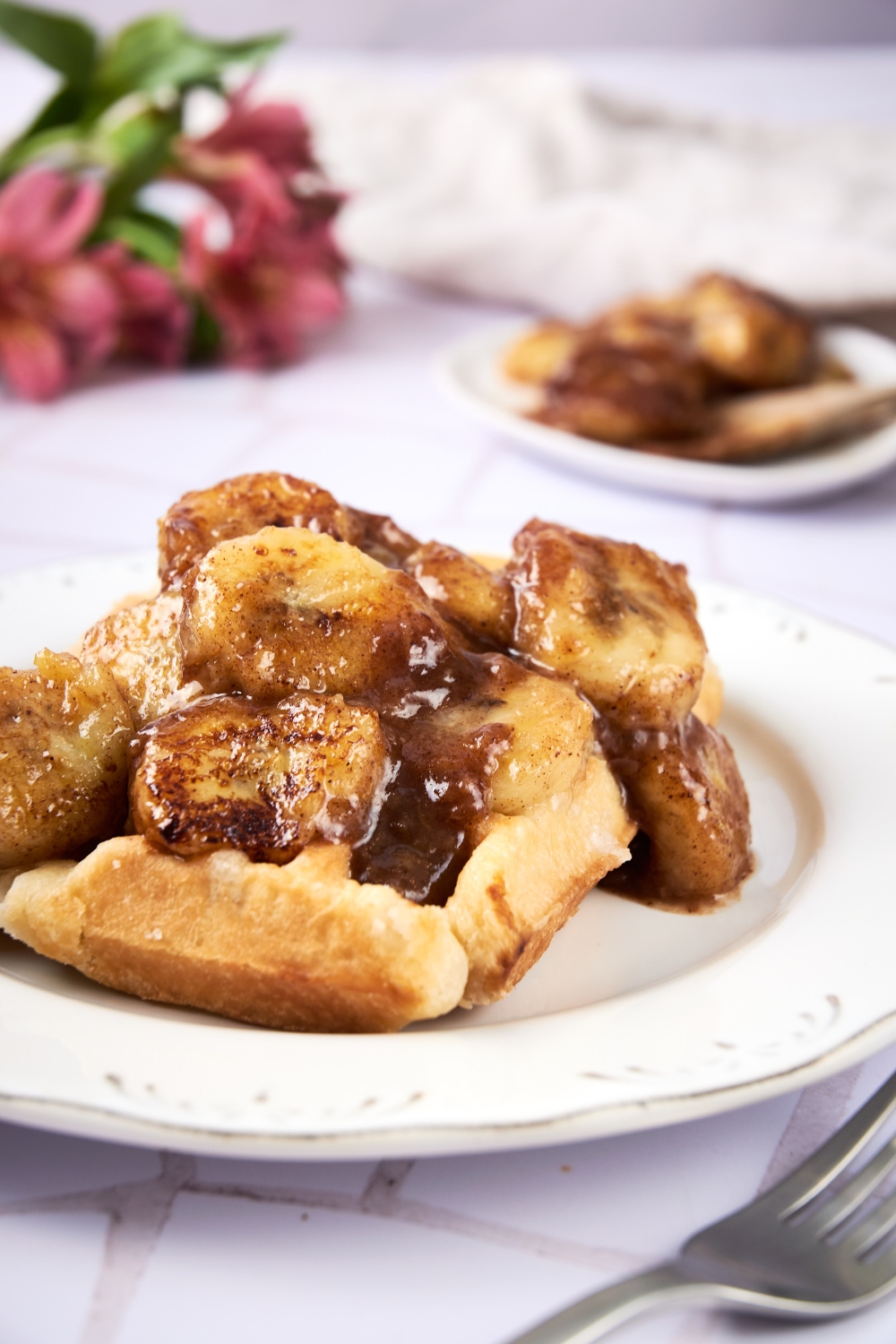 A plate with fried bananas served on top of a waffle.