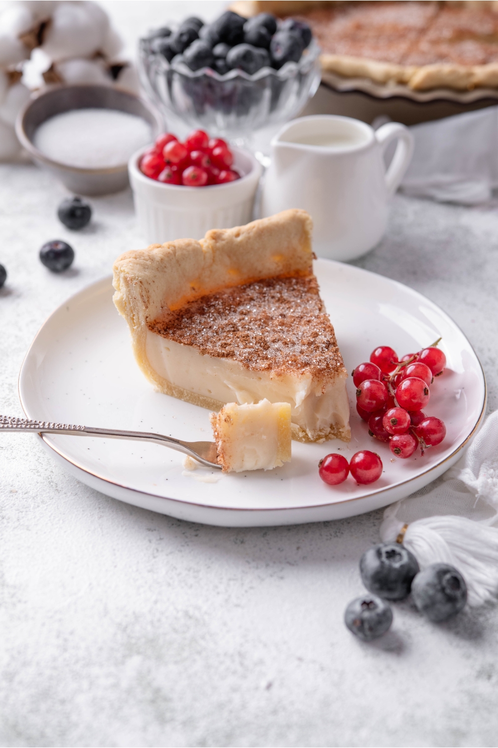 A small plate with a slice of sugar cream pie with grapes on the side.