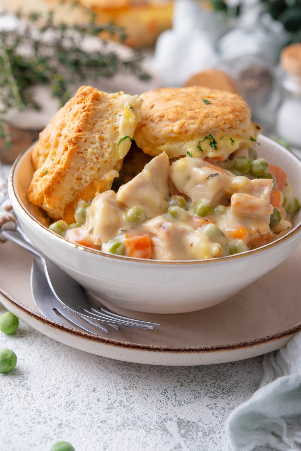 Turkey pot pie and two biscuits in a bowl on top of a plate.