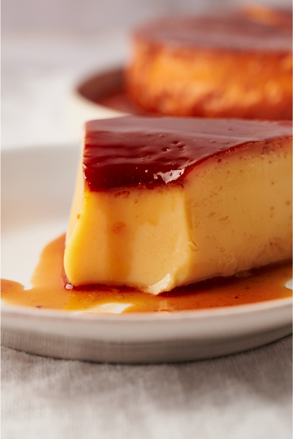 A small plate with a slice of flan and a bite taken out of it.