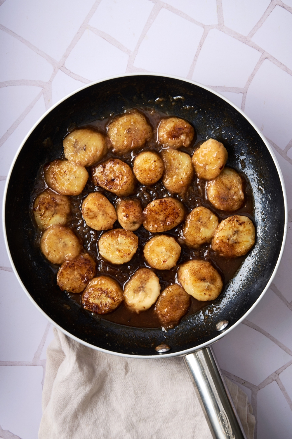 A frying pan with the cooked banana slices and honey mixture poured over it.