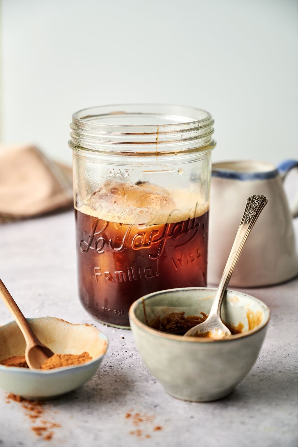 A mason jar with ice cubes and the shaken espresso.
